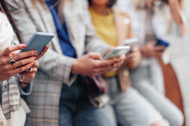 Detail van de handen van een Indiase vrouw die typt op de mobiele telefoon, mensen op de achtergrond die in de rij staan met mobiele telefoons