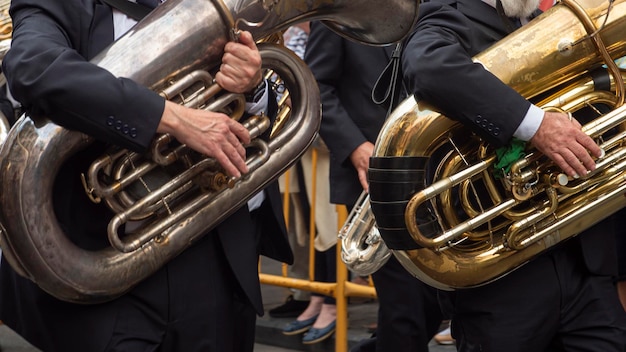 Foto detail van de handen van twee muzikanten die op straat paraderen en tuba spelen