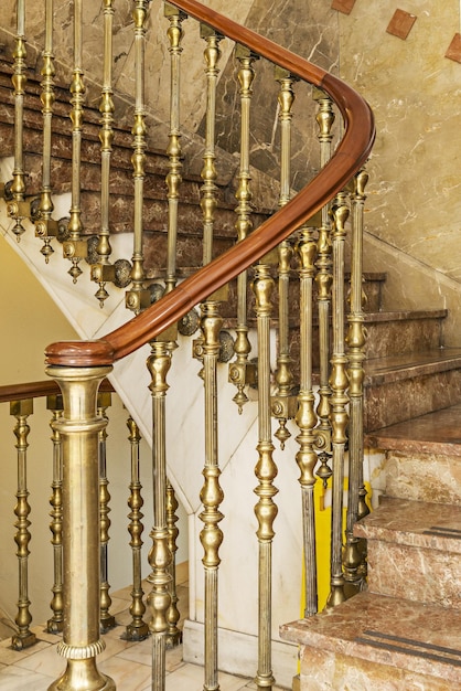 Foto detail van een gouden metalen marmeren trapleuning met een gelakte houten leuning