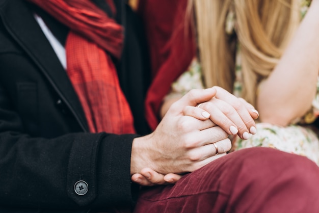 Detail van een jong verliefd koppel hand in hand en zittend in het park op een zonnige herfstdag. Selectieve aandacht. Relaties concept