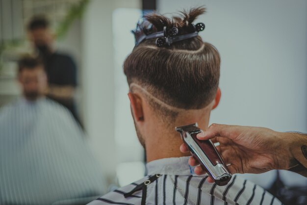 Detail van een jonge man die het haar van een man knipt in een kapperszaak