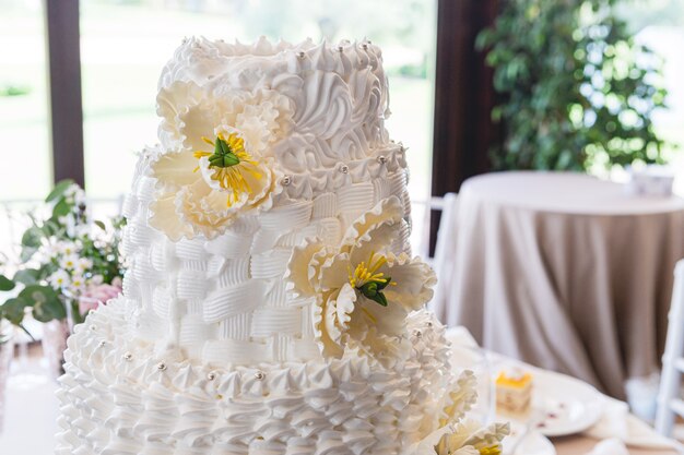 Detail van een prachtige crème bruidstaart versierd met fondant bloemen op een bruiloft feest tafel