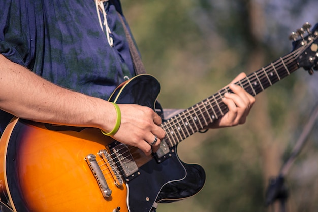 Detail van een rocker die zijn elektrische gitaar speelt tijdens een live concert.