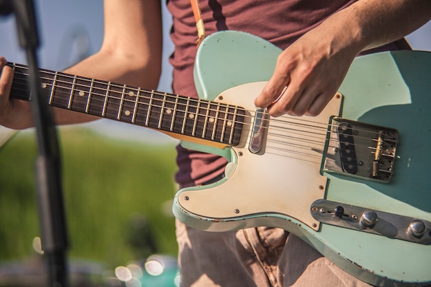 Detail van een rockmuzikant die een elektrische gitaar speelt