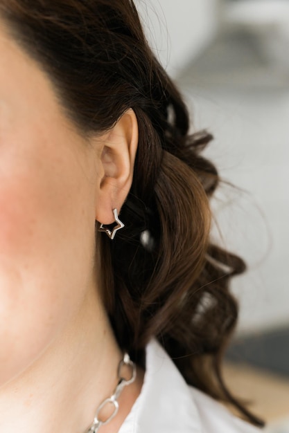 Detail van een vrouw die een mooie, luxe oorring draagt, met de hand gemaakte sieraden in de vorm van een ster