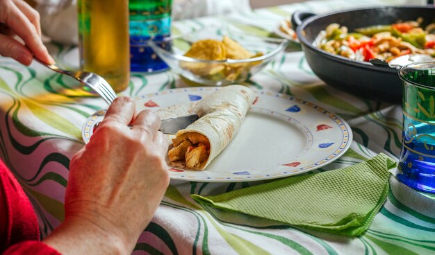 Detail van een vrouw die Mexicaanse fajita op het bord rolt