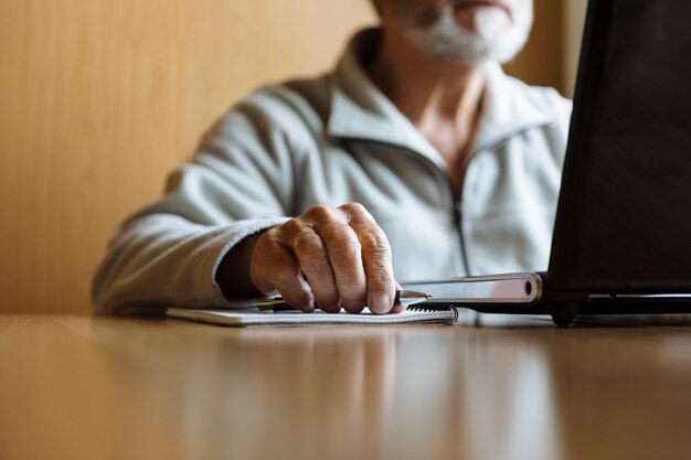 Detail van hogere man handen die aan laptop werken