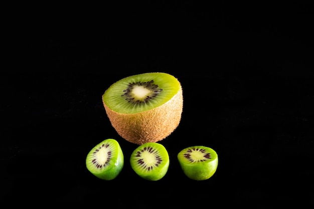 Detail van kiwi's van verschillende variëteiten Groene Kiwi en Baby Kiwi met zwarte achtergrond