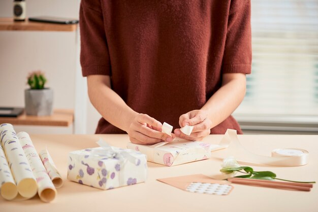 Detail van vrouwenhanden die cadeautjes inpakken met cadeaupapier