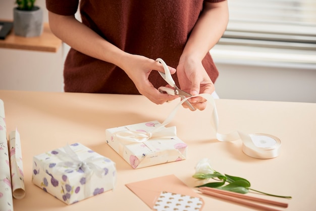 Detail van vrouwenhanden die cadeautjes inpakken met cadeaupapier