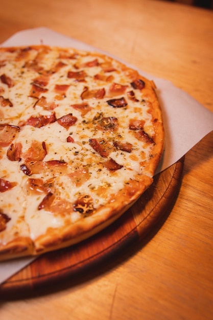 Detail view of half of a bacon pizza on a wooden table