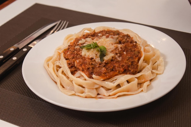 Detail view of a noodle with meat and sauce served on a white table