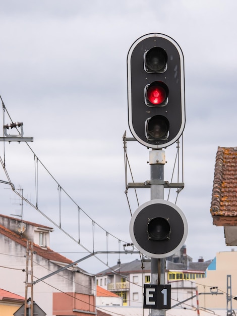 写真 曇り空を背景に停車時に赤い色の上部表示を与え、他の2つのランプをオフにするポール上の高い鉄道信号e1信号の詳細図