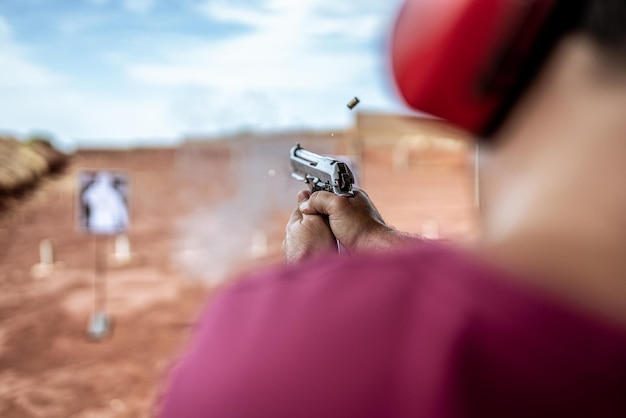 Detail view of shooter holding gun and training tactical shooting, focus on pistol. Shooting range.