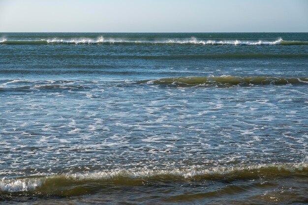 Photo detail of the waves of the atlantic sea beating on the golden sand beach during the summer holidays in the province of huelva spain