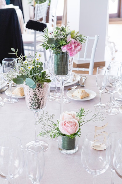 Detail of a wedding table with bouquet of pink roses and green leaves as decoration