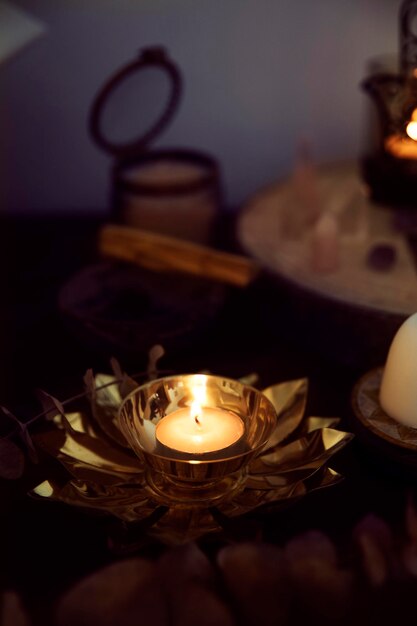 Detail of a white candle on a golden flowershaped candle holder on a witch's altar to perform rituals