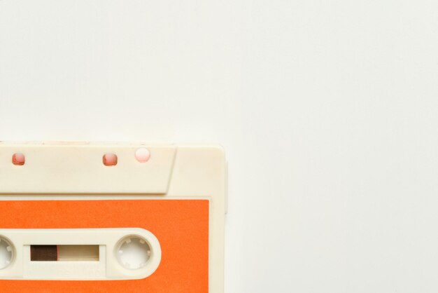 Detail of white old cassette tape with orange label in a corner of the photo on white background