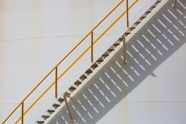 Detail of white tanks oil in tank farm with iron shadow staircase