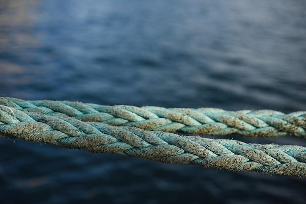 Foto dettaglio di corda usurata sul molo con il mare sullo sfondo