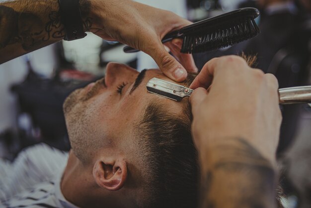 젊은 남자의 세부 사항은 이발소에서 남자의 머리카락을 자른다.