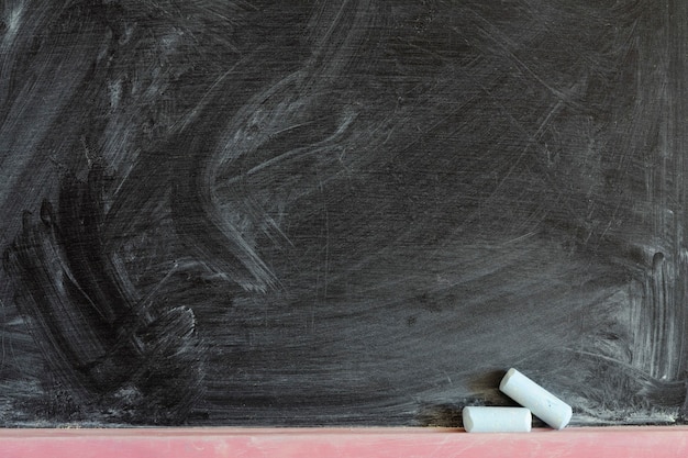 Detailed black chalkboard fragment with two chalk pieces