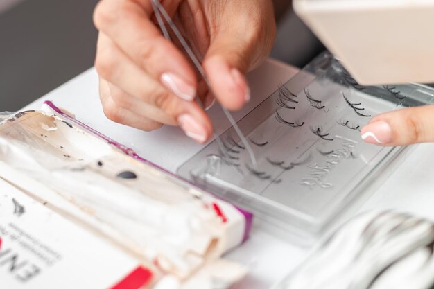 Detailed shot of a girl's hands grasping false eyelashes with tweezers