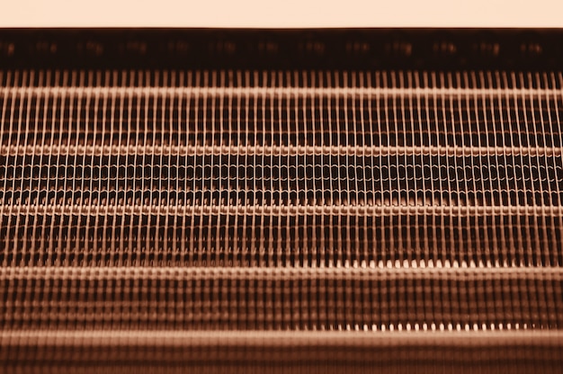 Detailed texture of engine water cooling radiator with horizontal lines. Background image of orange automobile part with copy space close up.