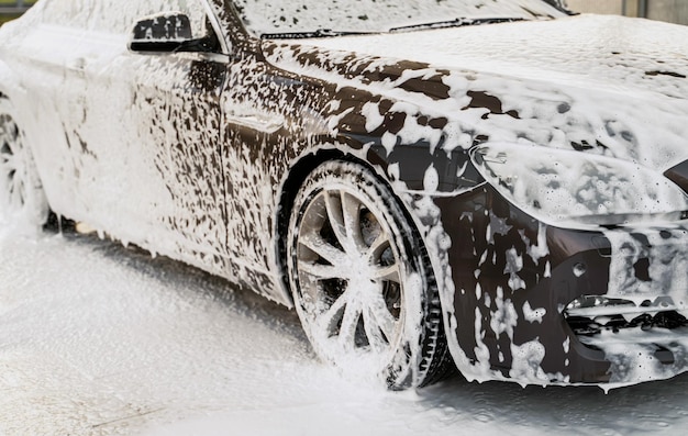 Detailed view of the car doused with white foam water and soap for car wash manual car wash