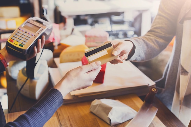 Detailhandel, creditcardbetalingsservice. Klant betaalt voor bestelling van kaas in kruidenierswinkel.