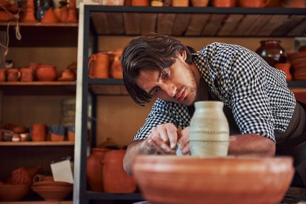 Detailing by special tool. Ceramist uses potter's wheel and creates a handmade clay product.