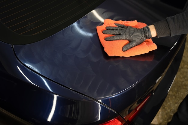 Detailing master applies wax for polishing on the vehicle body