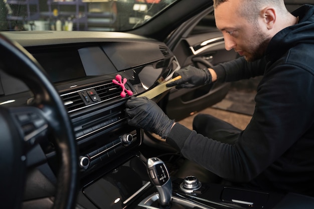 Detailing worker pasting protective tape on the car interior