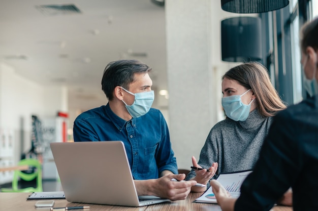 Detailopname. collega's in beschermende maskers zitten op kantoor.