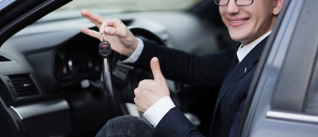 Detailopname. gelukkige chauffeur die duim opsteekt terwijl hij in zijn auto zit