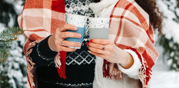 Detailopname. man en vrouw met kopjes warme chocolademelk met room in winterbos