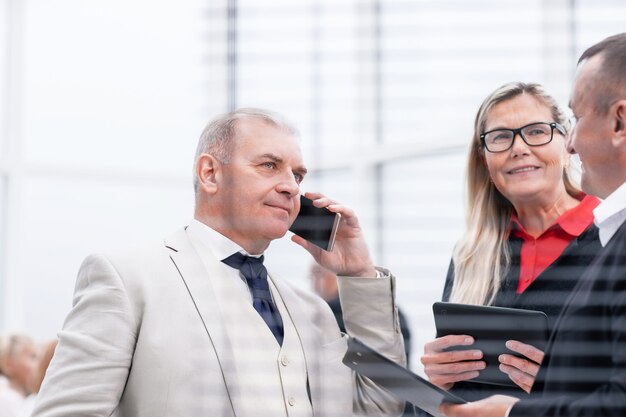 Detailopname. serieuze zakenman praten op zijn smartphone die op kantoor staat. kantoor weekdagen