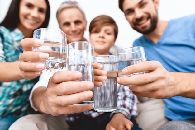 Detailopname. Vrolijke familie juichen met glazen water.