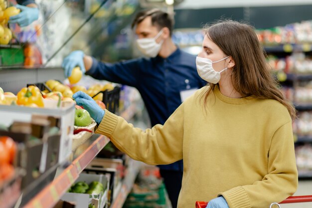 Detailopname. vrouwelijke klant die in beschermende handschoenen fruit kiest in de winkel. concept van bescherming van de gezondheid.