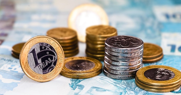 Details of banknotes of 100 reais from brazil, and brazilian coins, with selective focus, background image. Concept of investment in brazil or profit.