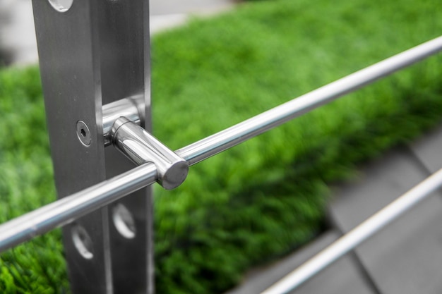 Details of fence made of stainless steel profile with an artificial raffa on the background