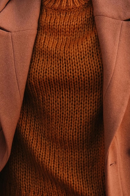 Details of orange warm cozy female sweater and brown coat Outdoor autumn winter street style