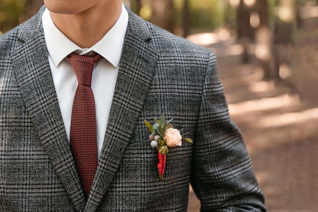 Details over het jasje van de bruidegom Boutonniere van verse bloemen rode stropdas en grijs pak