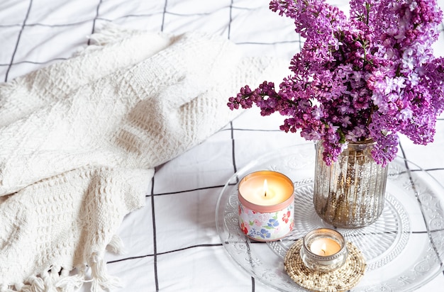 Details van een gezellige inrichting en een boeket verse lila bloemen op een lichte tafel.