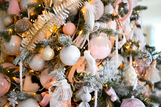 Details van een kerstversierde boom in zachte roze kleuren.