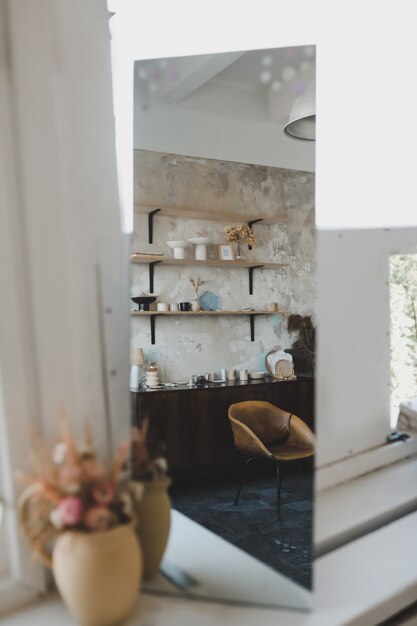 Foto details van een modern stijlvol creatief interieur van een woonkamer met een spiegel en bloemen in een vaas