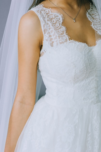 Details of a wedding dress. Close up of faceless girl in beautiful white wedding dress. Bride's accessories.