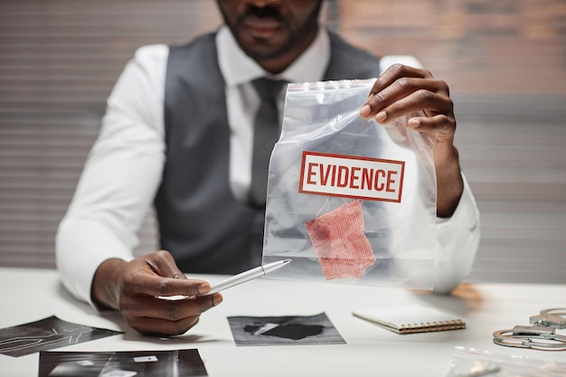 Detective holding plastic bag with evidence during interrogation