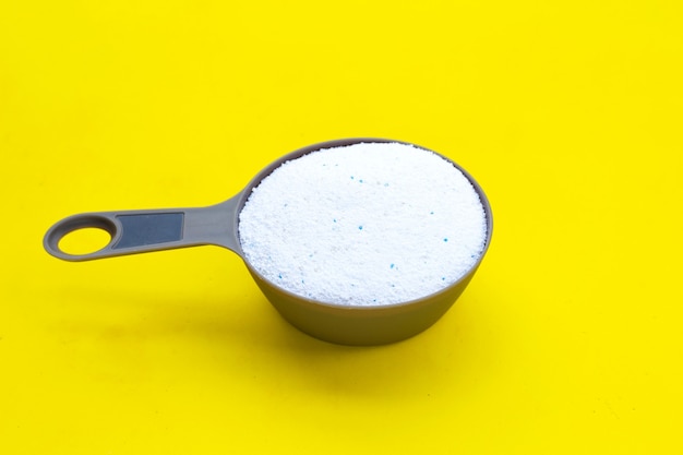 Detergent powder in measuring spoon for clothes washing