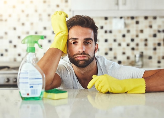detergent sponge and portrait of bored man in kitchen at home for sanitizing germs bacteria or dirt removal gloves housekeeping and male person cleaning for hygiene of dust in apartment